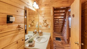 Une salle de bain de style rustique, avec des murs en bois, un lavabo blanc, un miroir et des porte-serviettes.