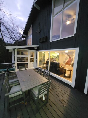 Une maison moderne dotée d’une terrasse, d’un coin repas avec des chaises et d’un escalier menant à un étage supérieur.