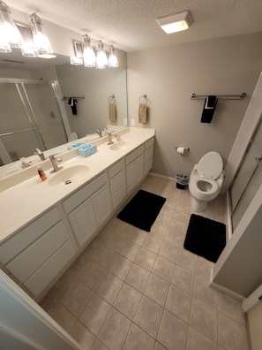 Une salle de bain moderne dotée d’un grand meuble-lavabo, de toilettes et d’un espace douche.