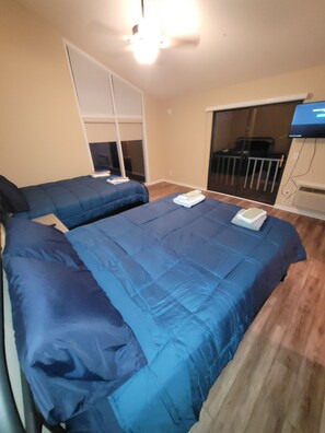Une chambre avec deux lits, une télévision et un balcon.