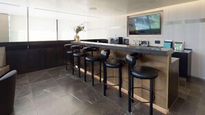A modern kitchen with a bar area, including a large TV, bar stools, and a vase with flowers. - Liverpool Street, Shoreditch by Interhome (Shoreditch)