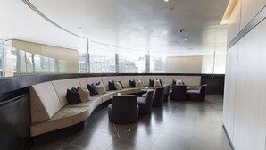 A modern lounge area with a curved seating arrangement, large windows, and a high ceiling. - Liverpool Street, Shoreditch by Interhome (Shoreditch)