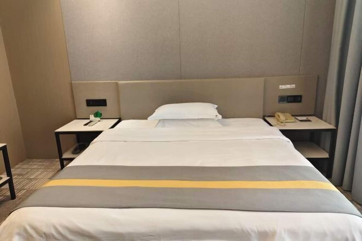A hotel room with a large bed, two bedside tables, a nightstand, and a headboard.