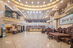 Eine großzügige Lobby mit einer Rezeption, einer Sitzecke und mehreren Ebenen mit Balkonen.