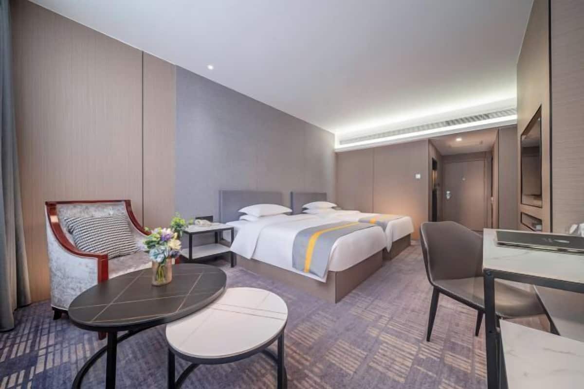 A hotel room with a bed, a desk, a chair, and a small table.