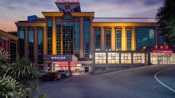 A hotel with a modern facade, large windows, and a parking lot.