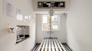 Una habitación con un banco de madera, una lámpara colgante y una ventana con persianas.