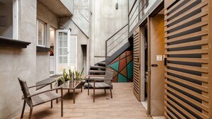 Un espacio exterior moderno con una mesa y sillas, una escalera y la puerta cerrada de una tienda.