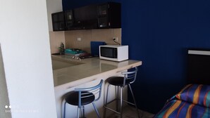 A small kitchenette with a microwave, a sink, and two bar stools. - Suite Frente AL MAR (Cancún)