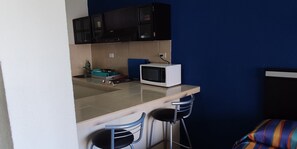 A small kitchenette with a microwave, a sink, and two bar stools. - Suite Frente AL MAR (Cancún)