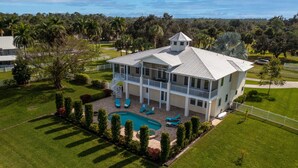 A large, two-story house with a swimming pool, surrounded by well-maintained lawns and trees. - Riverview Paradise, Sleeps 18, River, Pool/Spa, kayaks  (Alva)