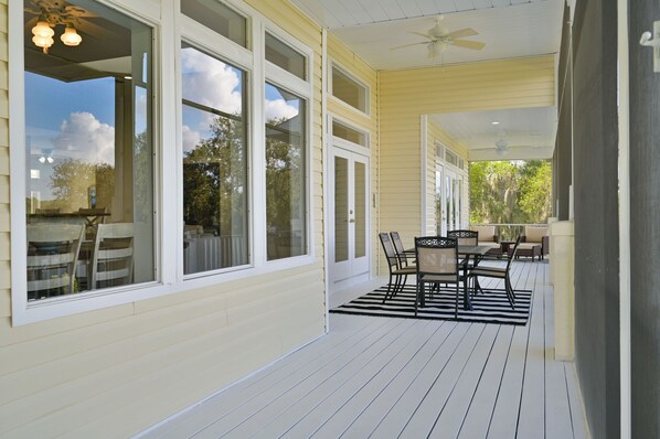 A covered patio with a dining area, large windows, and ceiling fans. - Riverview Paradise, Sleeps 18, River, Pool/Spa, kayaks (Alva)