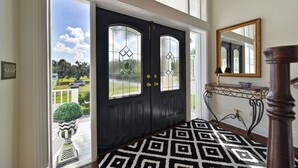 A black front door with glass panels, a patterned rug, a console table with a mirror, and a potted plant outside. - Riverview Paradise, Sleeps 18, River, Pool/Spa, kayaks  (Alva)