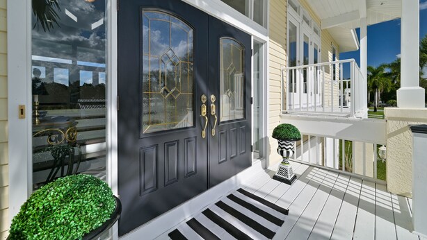 A dark front door with gold handles, a white porch railing, and a small potted plant. - Riverview Paradise, Sleeps 18, River, Pool/Spa, kayaks  (Alva)
