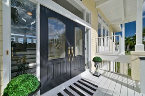 A dark front door with gold handles, a white porch railing, and a small potted plant. - Riverview Paradise, Sleeps 18, River, Pool/Spa, kayaks (Alva)