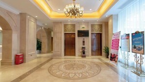 A spacious lobby with a central circular floor design, two elevators, a chandelier, and a red trash bin. - Vienna Hotel (Zhongshan Plaza) (Zhongshan)