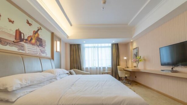 A hotel room with a large bed, a desk, a television, and a window with curtains. - Vienna Hotel (Zhongshan Plaza) (Zhongshan)