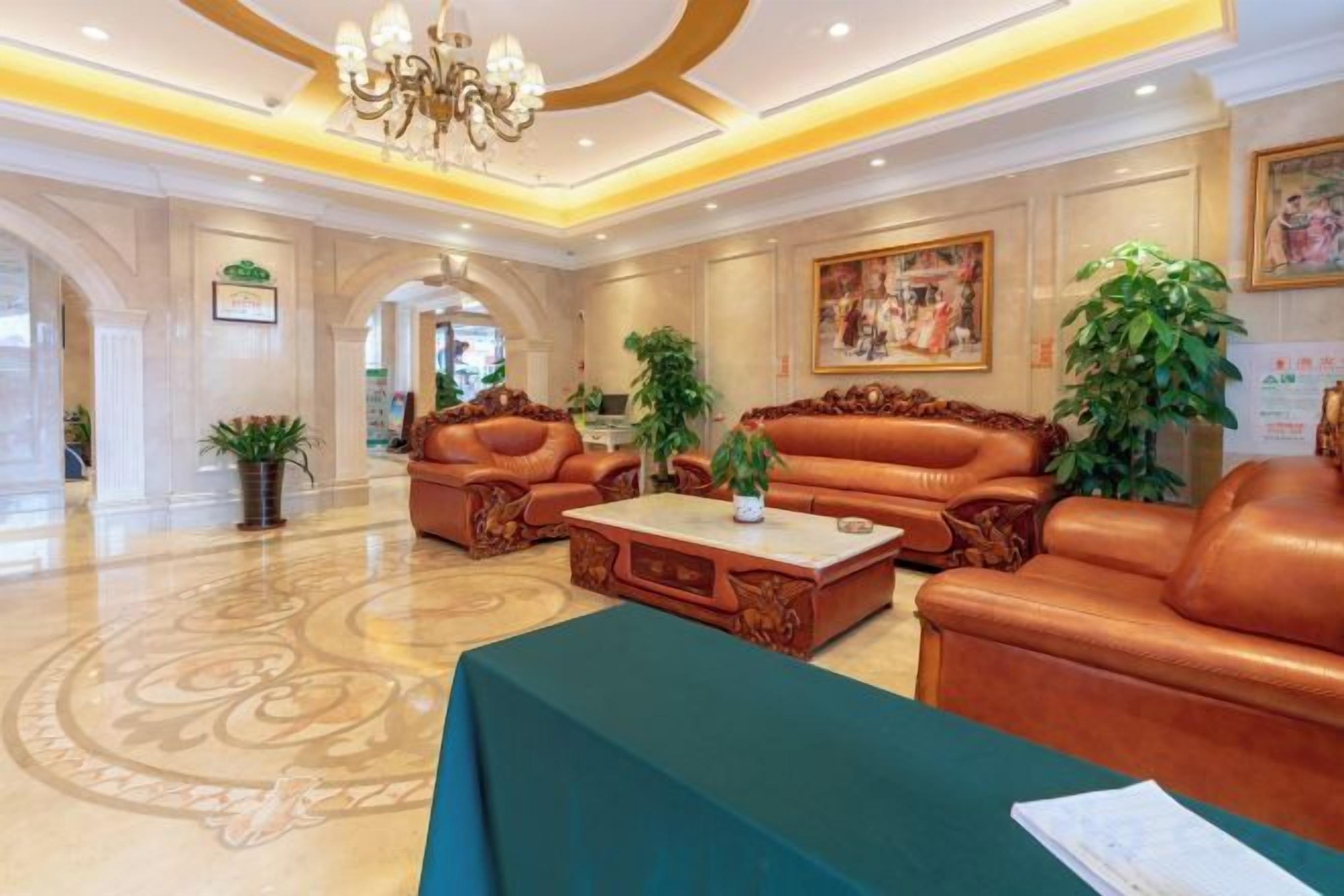 A lobby with leather sofas, a coffee table, and a chandelier.