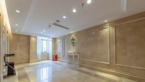A spacious hallway with a polished marble floor, a small table with a telephone, and a red trash bin. - Vienna Hotel (Zhongshan Plaza) (Zhongshan)