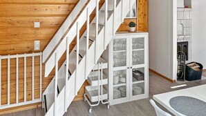 Una cocina moderna con armarios blancos, techo de madera y una escalera empotrada.