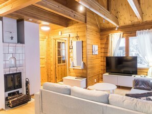 A cozy cabin interior with a fireplace, sofa, television, and wooden walls.