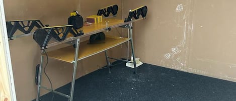A room with a metal table, a chair, and a black carpet.