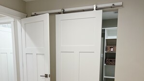 A bedroom with a bed, a closet with shelves, and a sliding door.