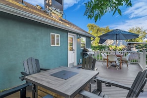 A wooden deck with a table and chairs, a grill, and a covered patio area.