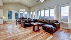 Un salón amplio con un sofá seccional de cuero grande, una mesa de centro de madera y una zona de comedor con candelabro.