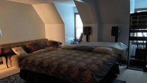 Un dormitorio con una cama grande, un sofá, una mesita y un altavoz.
