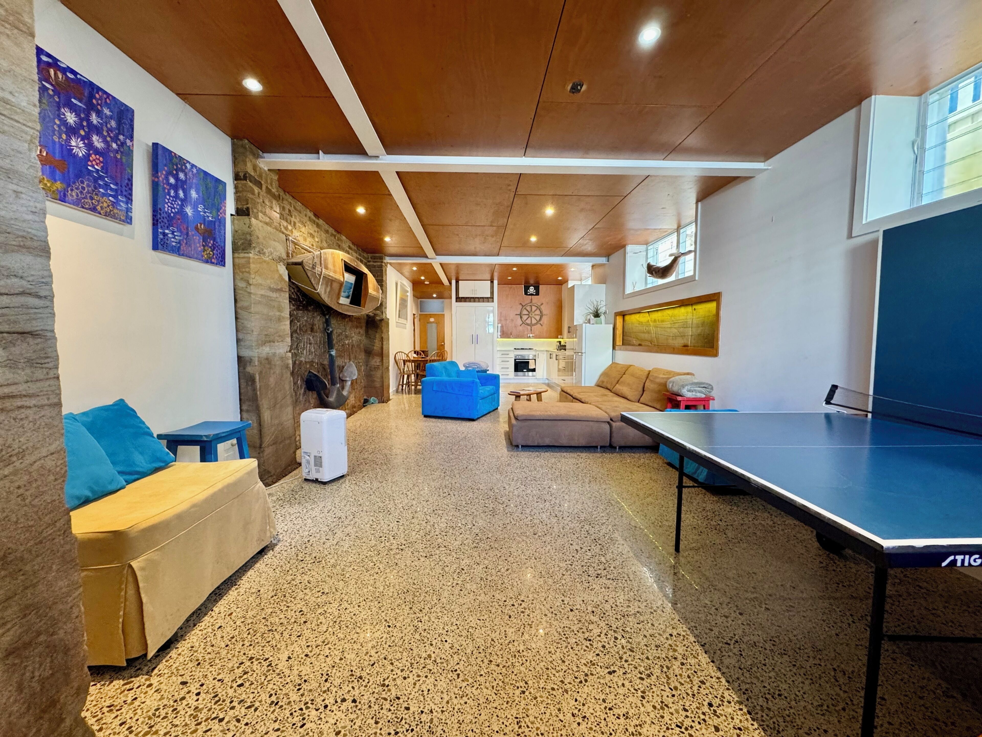 Un salon moderne avec une table de ping-pong, un mur en pierre et un coin salon confortable.