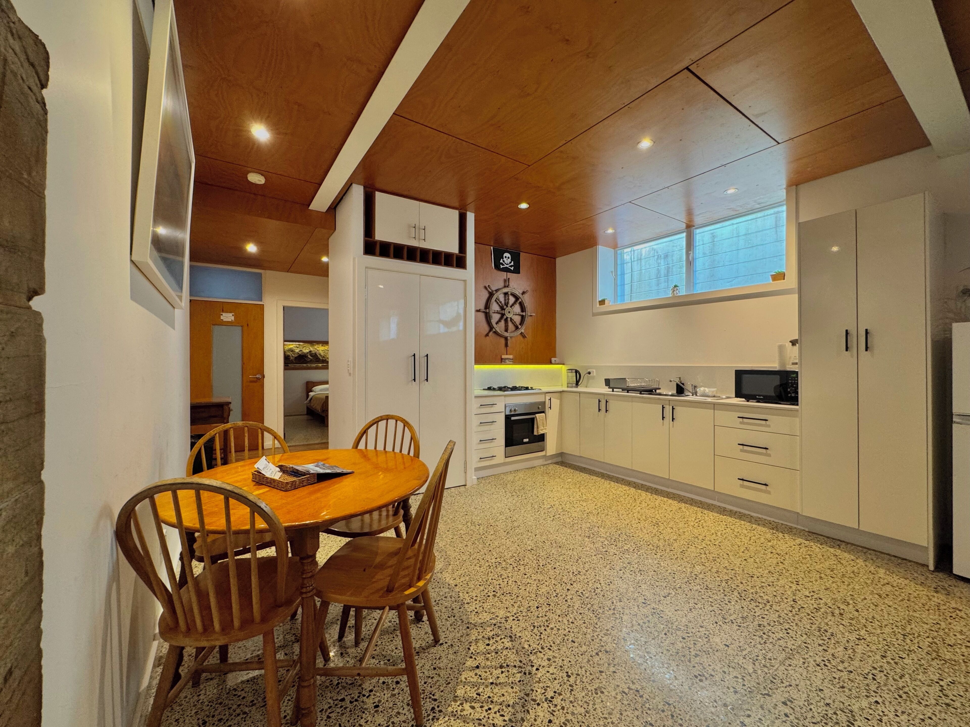 A kitchen with white cabinets, a wooden dining table, and chairs.