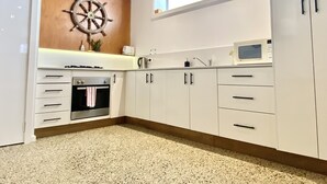 Una cocina con armarios blancos, un microondas, una estufa y un lavamanos.