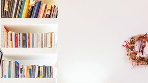 A neatly organized bedroom with a bookshelf, bedside table, and a bed.