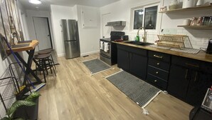 Une cuisine moderne dotée d’un réfrigérateur en acier inoxydable, de meubles noirs, d’un plan de travail en bois et d’un petit îlot central avec des tabourets.