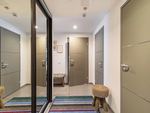 Un couloir doté de portes coulissantes, d’un banc et d’un tapis rayé aux couleurs vives.