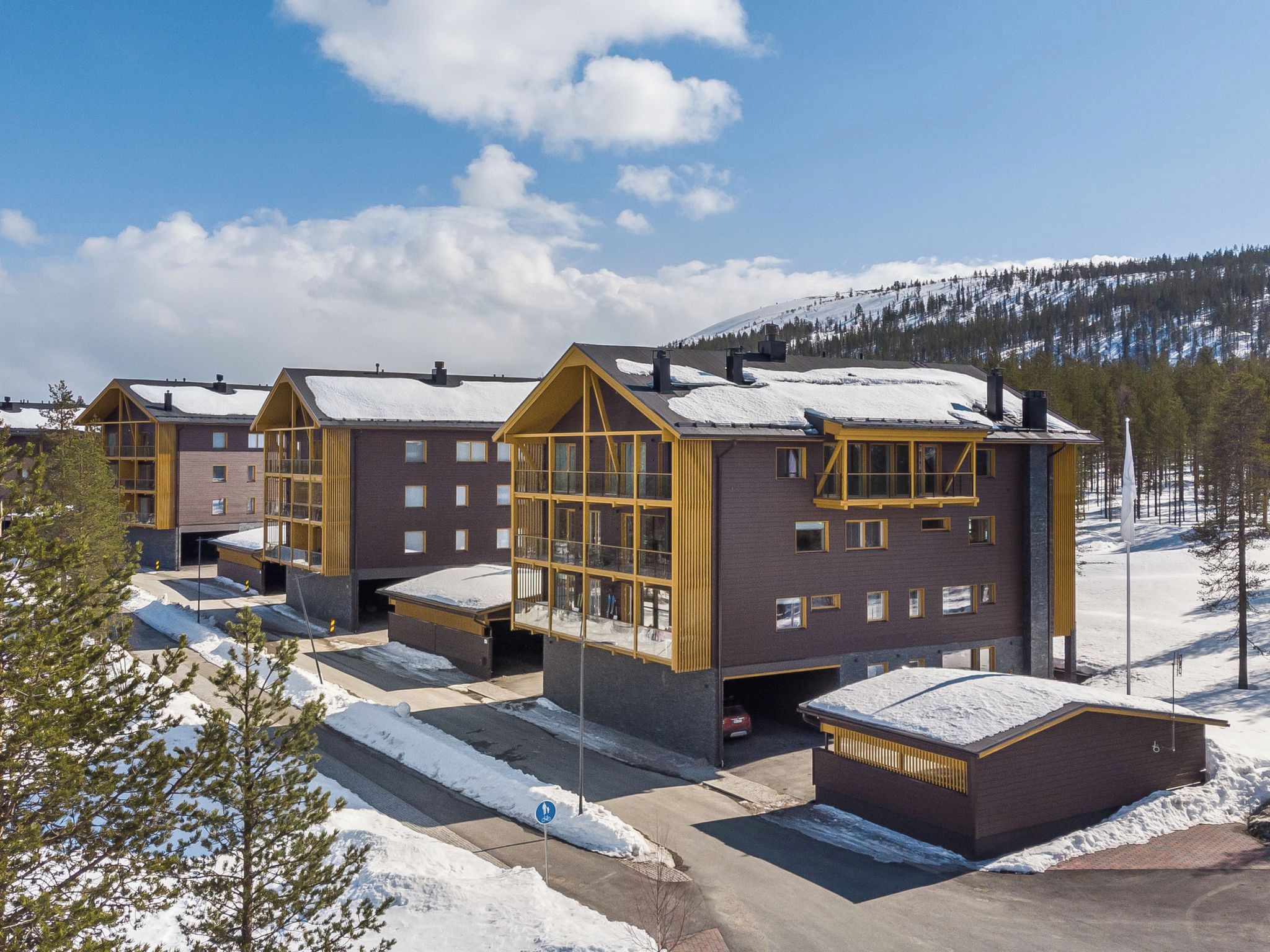 A multi-story hotel with a modern design, featuring large windows and a snow-covered roof.