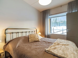 Une chambre à coucher avec un lit, une fenêtre donnant sur des arbres et une porte.