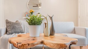 Una sala de estar moderna con una mesa de centro de madera, un sofá blanco y una planta en maceta.