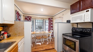 Una cocina compacta con estufa, microondas y comedor con sillas y mesa.
