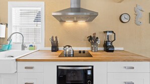 Een moderne keuken met witte kastjes, een roestvrijstalen waterkoker, een blender en een inbouwoven.