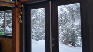 A room with large windows offering a view of snow-covered trees. - Luxurious Quonset hut in the woods, mountain views (Kila)