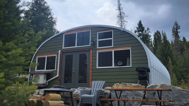 A dome-shaped cabin with a front door, two windows, and a small porch area. - Luxurious Quonset hut in the woods, mountain views (Kila)