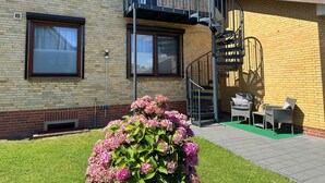 En toetagers bygning med facade af mursten, en balkon og en spiraltrappe.