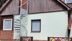 A wooden house with a spiral staircase, a brick wall, and a light-colored exterior. - Vacation in the Spreewald 2 Pers - Apartment for 2 persons (Golßen)