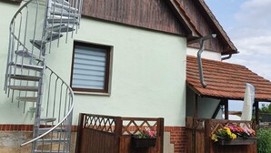 A rustic building with a spiral staircase, a wooden fence, and flower planters. - Vacation in the Spreewald 2 Pers - Apartment for 2 persons (Golßen)