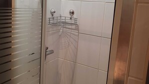 A shower with a glass door, a showerhead, and a metal shelf. - Vacation in the Spreewald 2 Pers - Apartment for 2 persons (Golßen)
