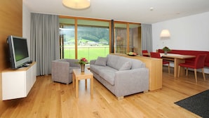 Een moderne woonkamer met een bank, televisie en eethoek.