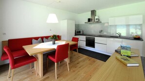 Een moderne keuken met witte kastjes, een magnetron en een koffiezetapparaat.
