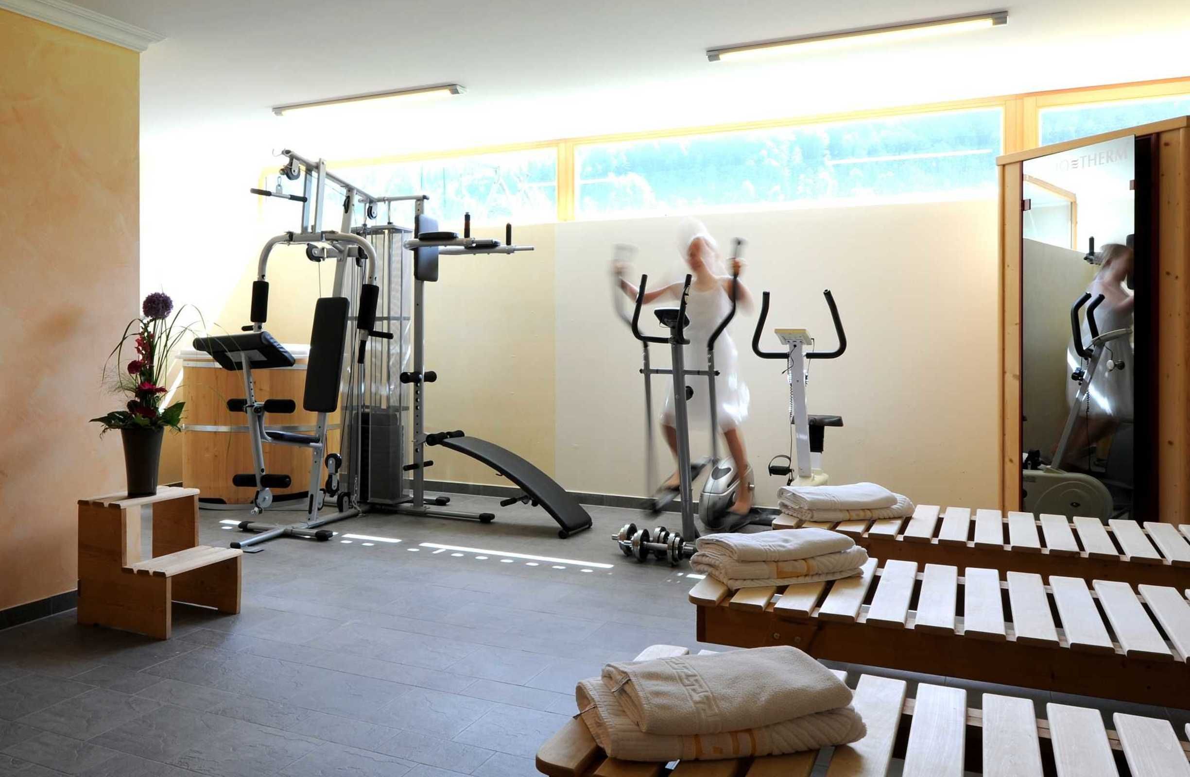 A gym with exercise equipment, a bench, and towels.